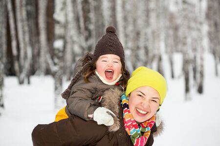 A mother holding her little daughter on her backの写真素材