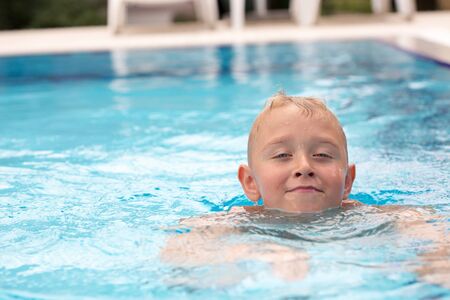 A cute blonde boy learning to swimの写真素材