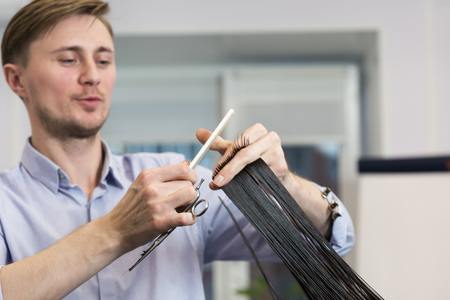 Handsome hairdresser making haircut of a brunette female client. Selective focusの写真素材