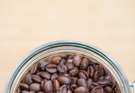 Coffee beans in a glass bowl on wooden background. Shallow dofの写真素材