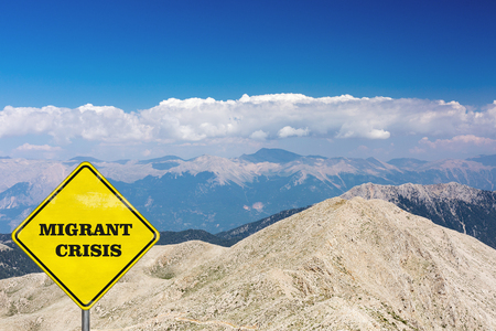 The road sign with Migrant crisis sign on a background with mountainsの写真素材