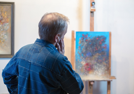 A male artist looking at his painting in studioの写真素材