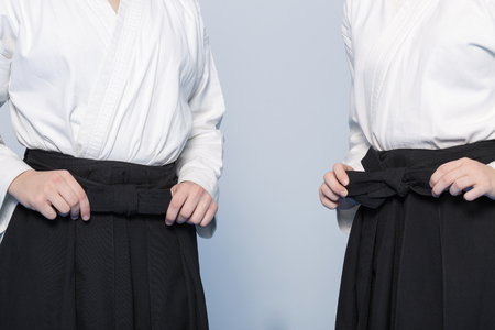 Girl's hands tie a bow-knot on hakama for martial arts trainingの写真素材