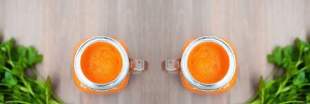 Two Healthy carrot smoothies in a jars on wooden background with parsley. Shallow dofの写真素材