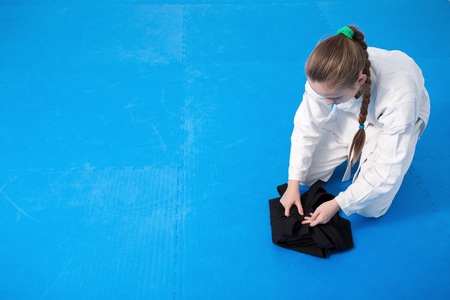 An aikidoka girl folding her hakama for Aikido training, sitting on tatamiの写真素材
