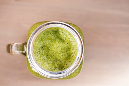 A top view of a green smoothie in a mason jar on wooden backgroundの写真素材