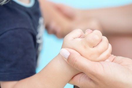 Toddler baby holding his mothers finger. Selective focusの写真素材