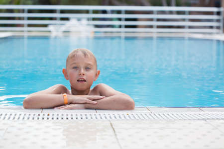 A blond boy learning to swim in a swimming poolの写真素材