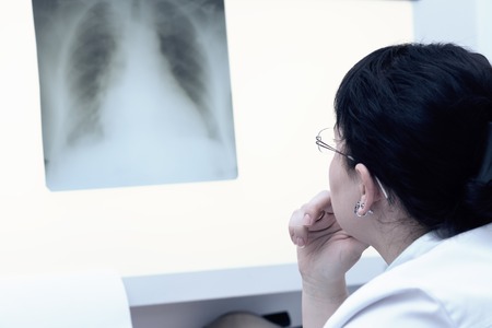Brunette female doctor examining an x-ray. Selective focus. Cold toningの写真素材