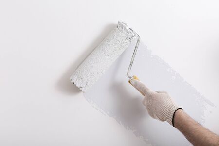 Close up of painter hand painting a wall grey with paint rollerの写真素材