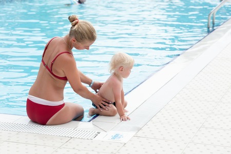 Blonde mother and her little son have fun by a swimming poolの写真素材