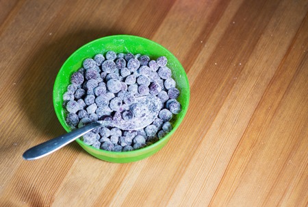 Baking muffins ingridients. Blueberries in a green bowl on wooden table backgroundの写真素材