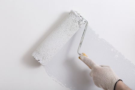 Close up of painter hand painting a wall grey with paint rollerの写真素材