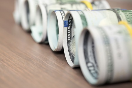 Rolls of one hundred US dollar bills on a wooden table. Shallow dofの写真素材