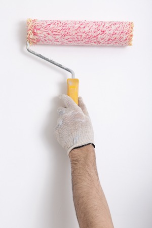 Close up of painter arm painting a wall with red paint roller