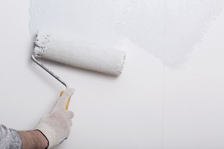 Close up of painter arm painting a wall in gray with paint rollerの写真素材