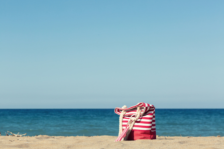 Beach bag on a sandy beach with a blue sea on a backgroundの写真素材