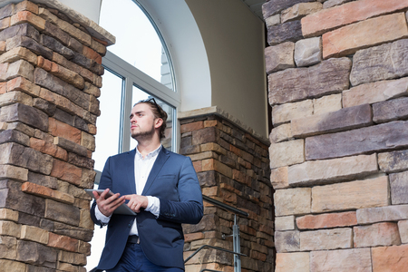 Young businessman wearing glasses using a tablet pc outdoorsの写真素材
