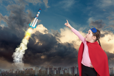 Cute little super hero girl in the red cloak and a speceshipの写真素材