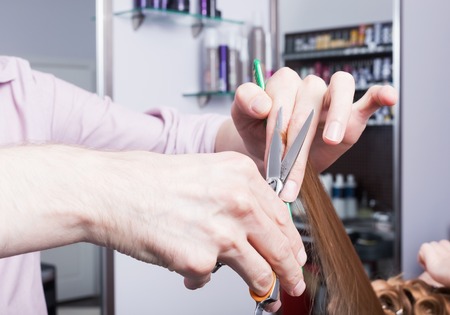 A hairdresser making a haircut for a blonde girlの写真素材