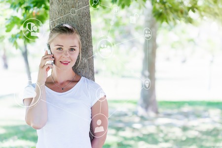 Beautiful blonde woman using smartphone in parkの写真素材