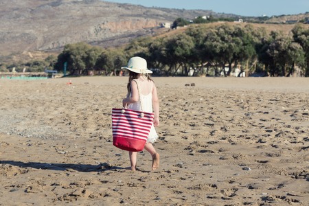 Little girl in white dress walking alone the seaの写真素材