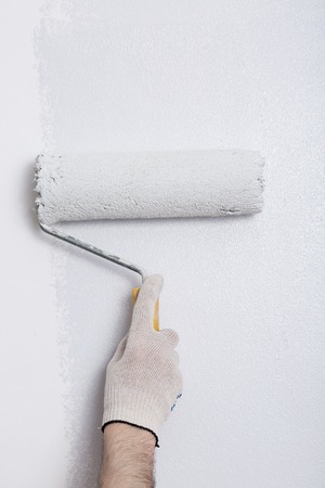 Close up of painter arm painting a wall with paint rollerの写真素材