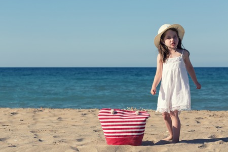 Little girl in white dress walking alone the seaの写真素材
