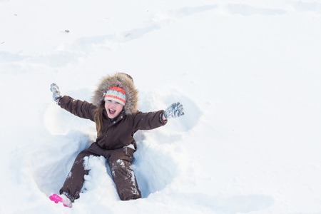 Beautiful little girl making a snow angelの写真素材