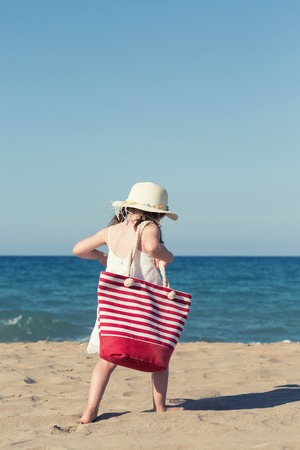 Little girl in white dress walking alone the seaの写真素材
