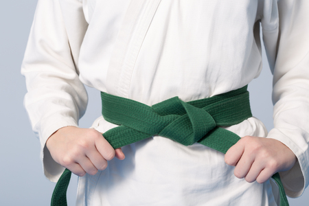 Hands tightening green belt on a teenage dressed in kimonoの写真素材