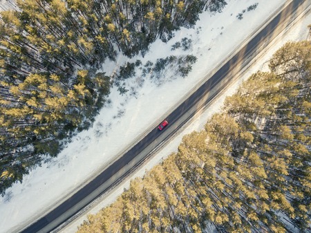 Snowy road with a moving car in winterの写真素材