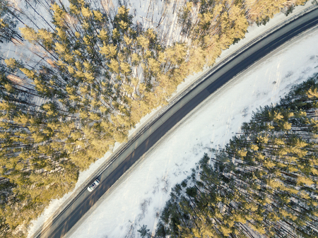 Snowy road with a moving car in winterの写真素材
