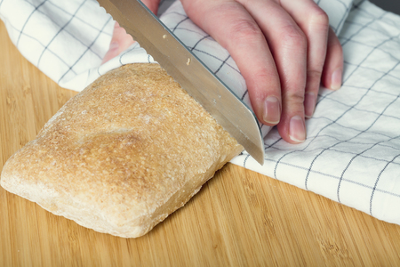 Female hands slicing rye breadの写真素材
