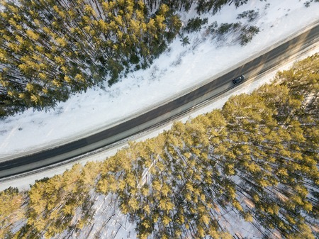 Snowy road with a moving car in winterの写真素材