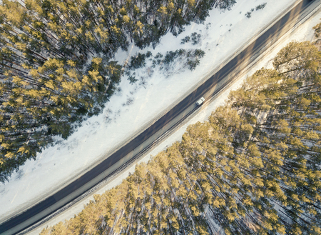 Snowy road with a moving car in winterの写真素材