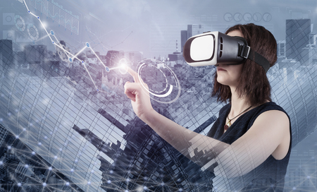 Woman in VR headset touching interface against modern city backgroundの写真素材