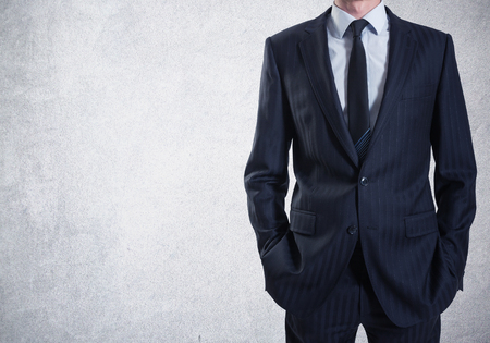 A man in suit on a concrete wall backgroundの写真素材
