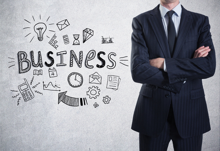 A man in suit on a concrete wall background with a business sketch on itの写真素材