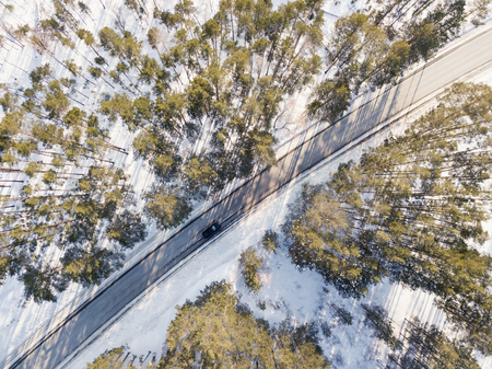 Snowy road with a moving car in winterの写真素材