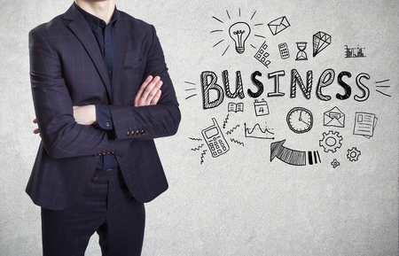 A man in suit on a concrete wall background with a business sketch on itの写真素材