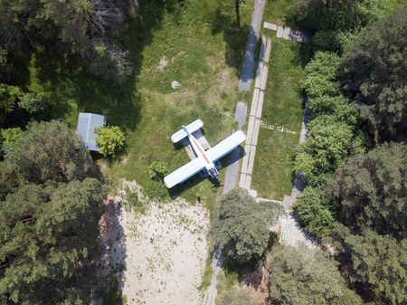 Old airplane standing in the pine forest. Aerial view from droneの写真素材