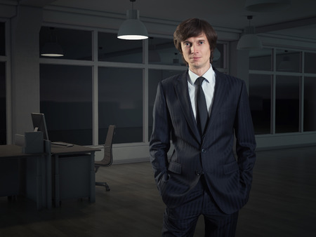 A businessman standing in night officeの写真素材