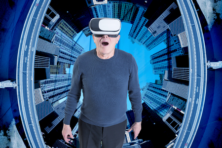 An old man in VR headset against a city buildings background.の写真素材