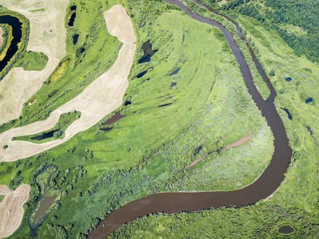 Aerial landscape of winding river in green fieldsの写真素材