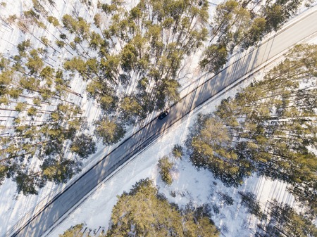 Snowy road with a moving car in winterの写真素材