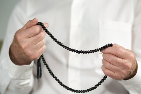 Praying hands of an old man with rosary beadsの写真素材
