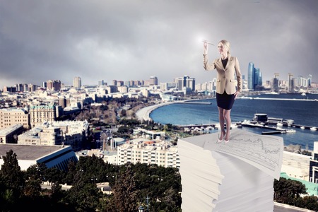 A Businesswoman standing on a stack of business papersの写真素材