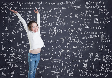 A little girl in front of the blackboard with formulas and calculationsの写真素材