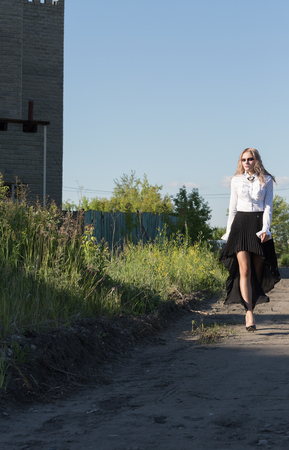 A girl walking along the road in a fieldの写真素材